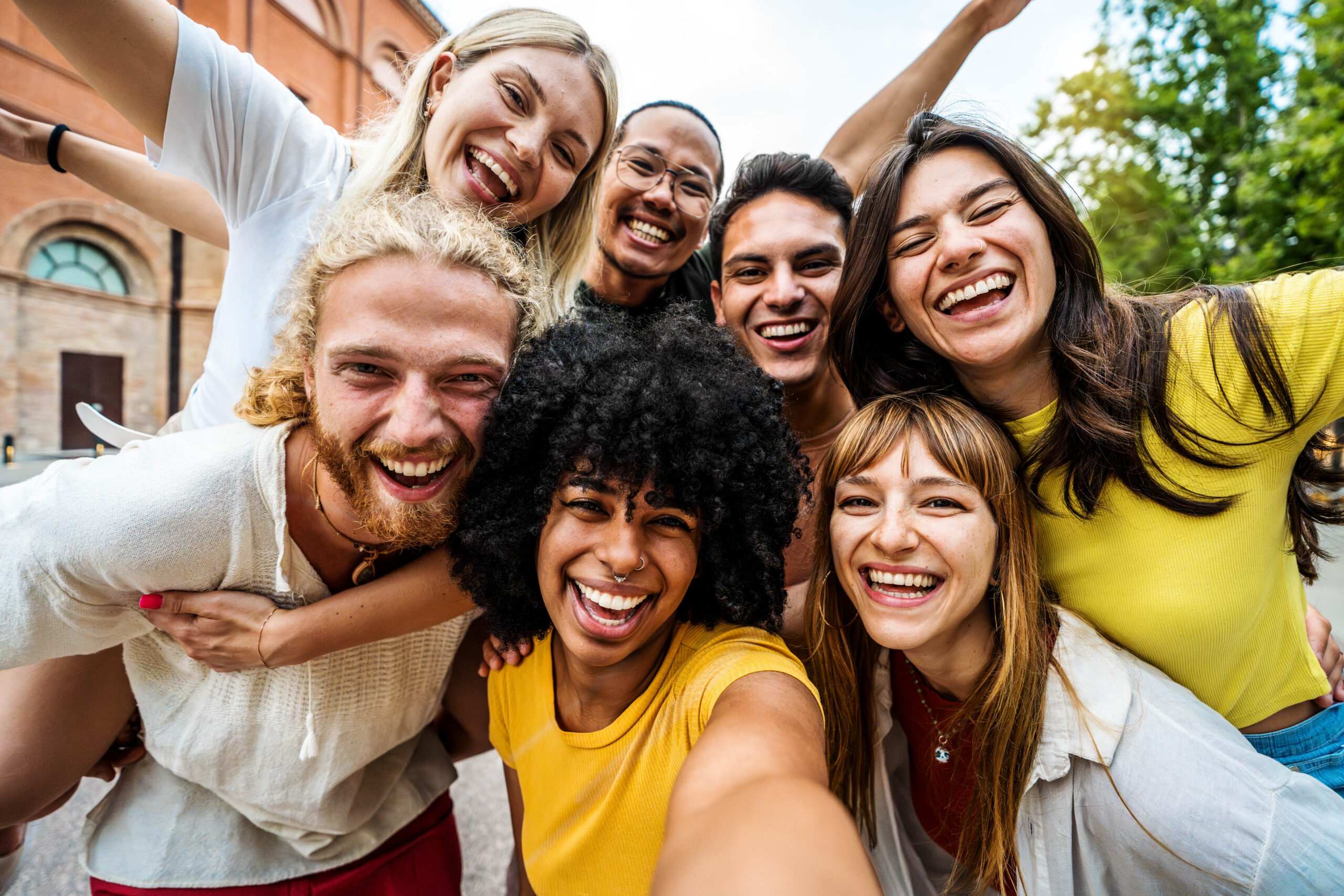 Multicultural friends smiling at camera together outside - Happy young people taking selfie with smart mobile phone device walking on city street - Youth community and technology concept